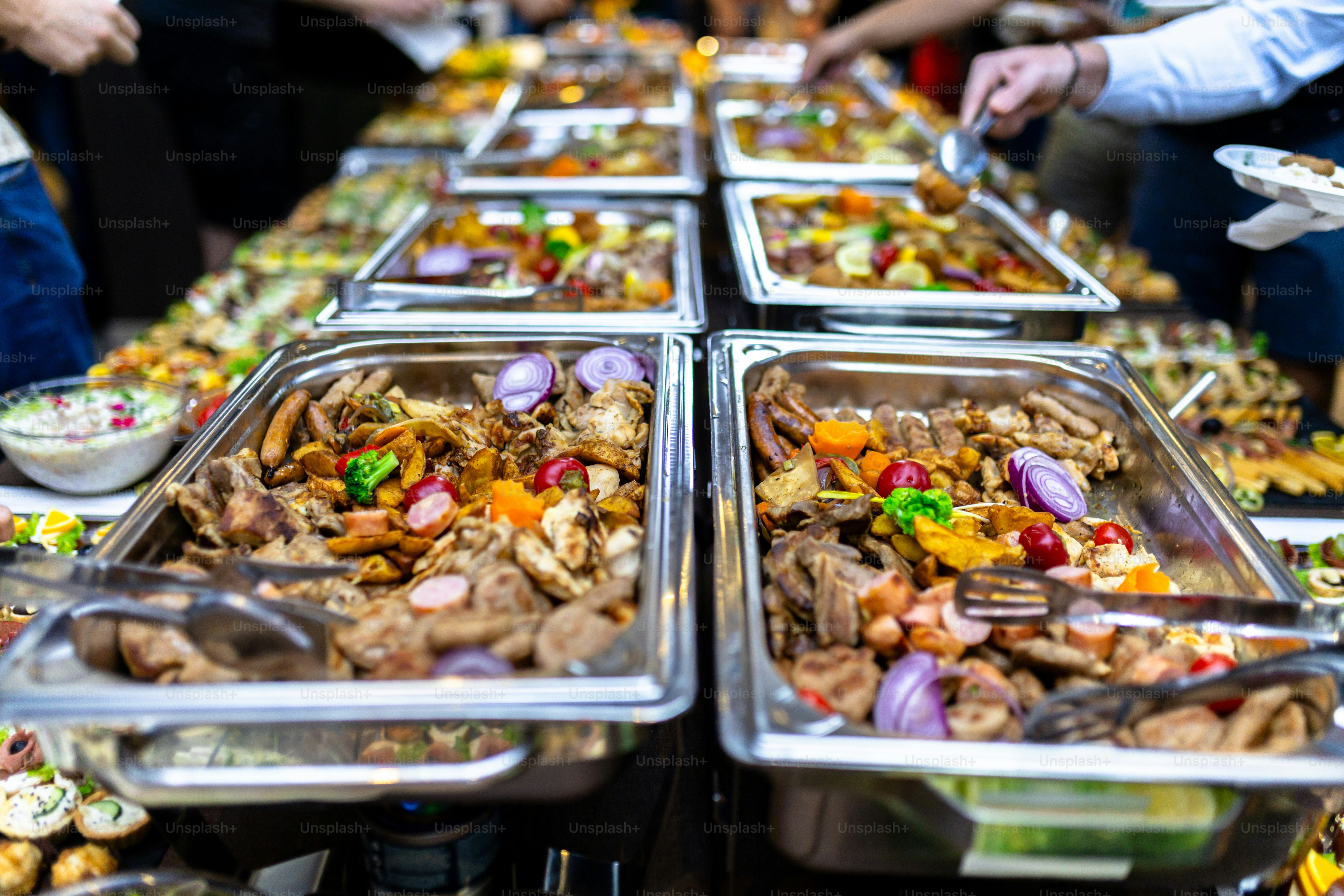 Guests enjoy a lavish buffet spread filled with various dishes, including meats, vegetables, and colorful garnishes at a lively evening event.